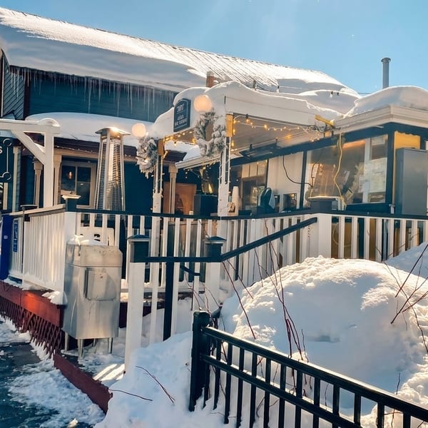 Crepes A La Cart restaurant exterior in winter, with snow-covered roofs and icicles.