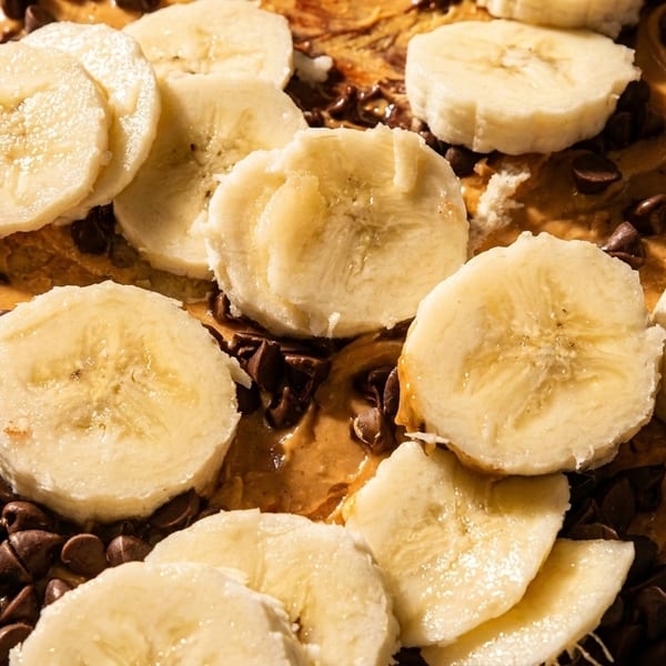 Close-up of a crepe topped with peanut butter, banana slices, and chocolate chips.